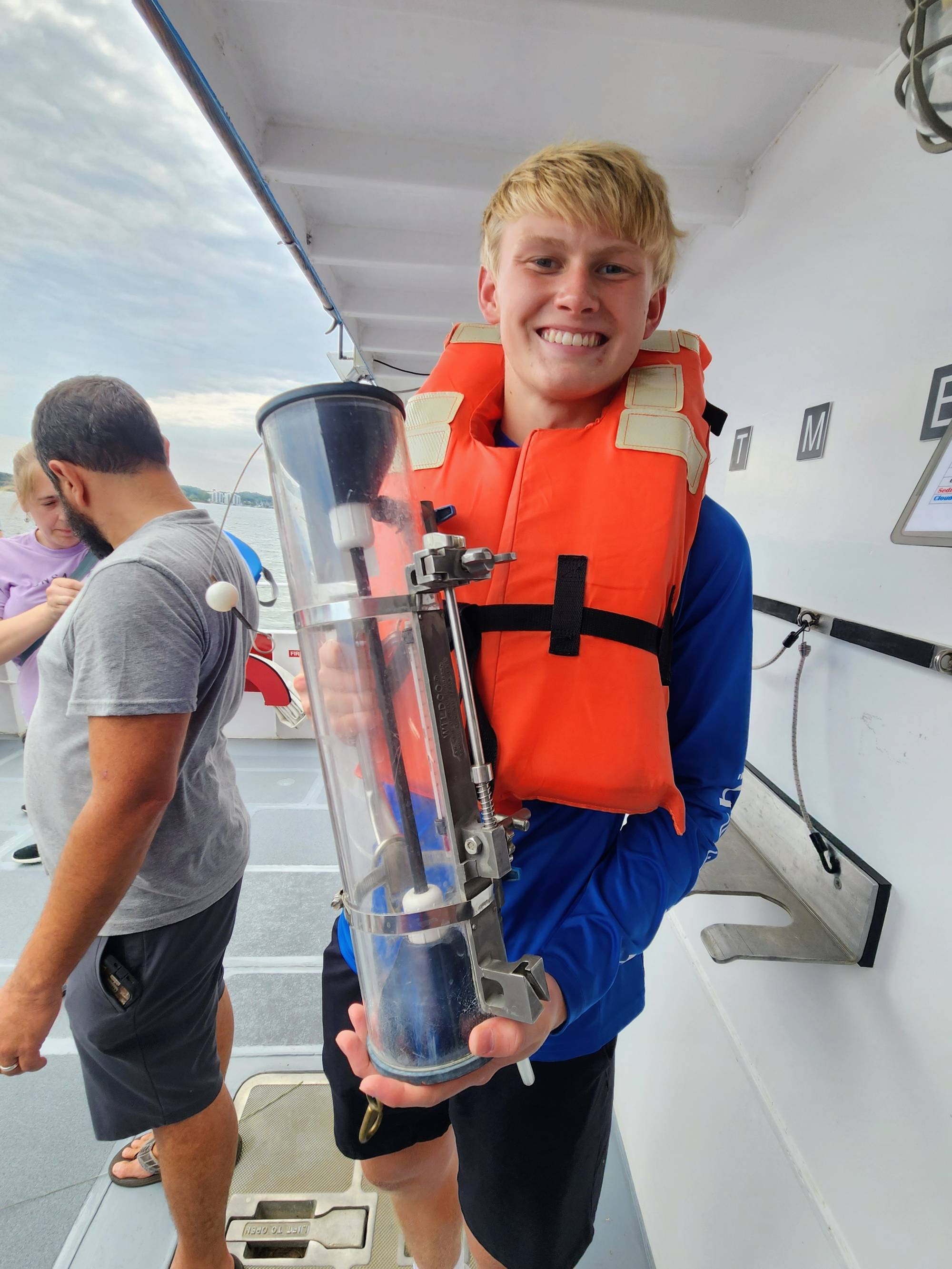 Student standing on the deck of the W.G. Jackson holding a VanDorn water bottle